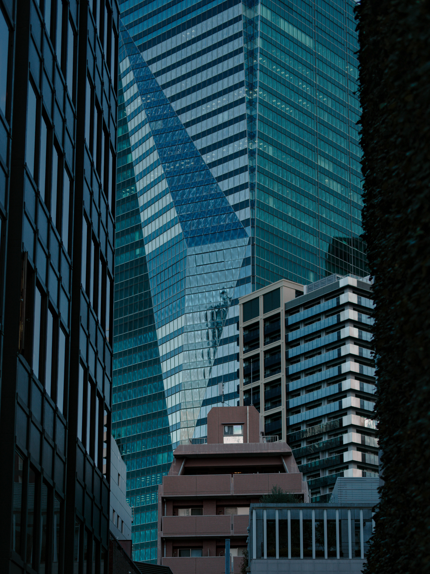 Overlapping glass buildings stand closely together by Meiji Maruo